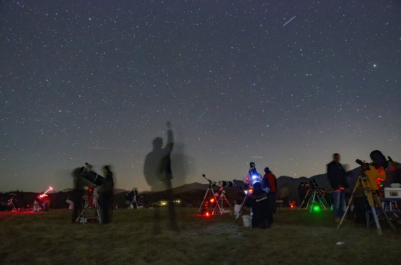 Druženje ob teleskopih: skupina udeležencev astronomskega opazovanja opazuje nočno nebo s teleskopi. Fotograf: Andrej Guštin